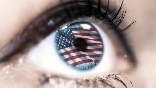 Frau-blaues-Auge-in-Nahaufnahme-mit-der-Flagge-der-USA-in-Iris-mit-Windbewegung.-Videokonzept