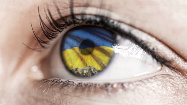 Frau-grünes-Auge-in-Nahaufnahme-mit-der-Flagge-der-Ukraine-in-Iris-mit-Windbewegung.-Videokonzept