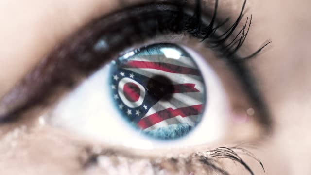 Mujer-ojo-azul-en-primer-plano-con-la-bandera-del-estado-de-Ohio-en-iris,-estados-unidos-de-América-con-movimiento-de-viento.-concepto-de-vídeo