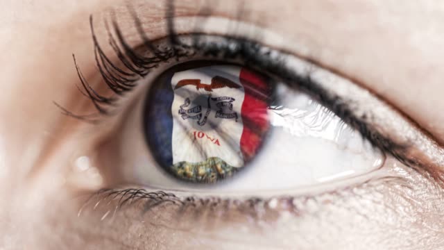 Woman-green-eye-in-close-up-with-the-flag-of-Iowa-state-in-iris,-united-states-of-america-with-wind-motion.-video-concept