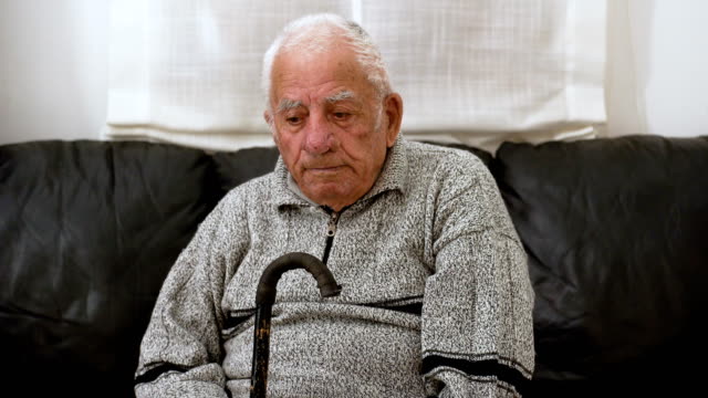 trauriger-einsamer-alter-Mann-sieht-die-Kamera-ruht-auf-seinen-Stock