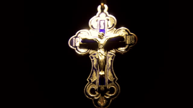 The-golden-cross-with-Jesus-Christ-on-the-chain-appears-from-the-darkness