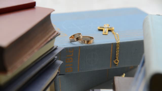 Two-wedding-rings-with-cros-in-the-bookshelh,-zoom-in,shot-with-slider