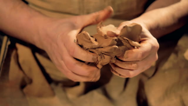 Potters-fingers-knead-a-medium-lump-of-brown-clay.