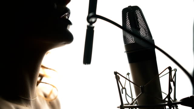 Beautiful-woman-singing-into-a-microphone-in-a-recording-studio.