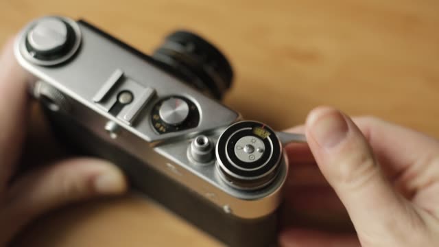 Eine-alte-Vintage-Filmkamera-in-den-Händen-von-einem-jungen-Anfänger-in-Sachen-Fotografie.-Er-spult-den-Film-zurück-und-nimmt-ein-Bild