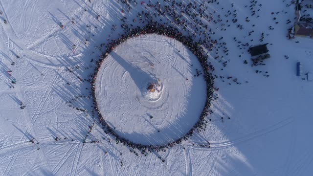 Kreis-von-Menschen,-die-während-der-Feier-des-russischen-traditionellen-Masleniza-Dummy-brennen-zu-sehen.-Filmmaterial.-Luftbild