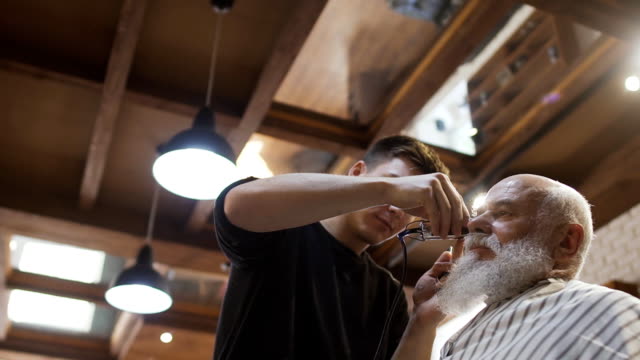 Friseur-schneidet-Grauhaarigen-älteren-Mann-in-barbershop