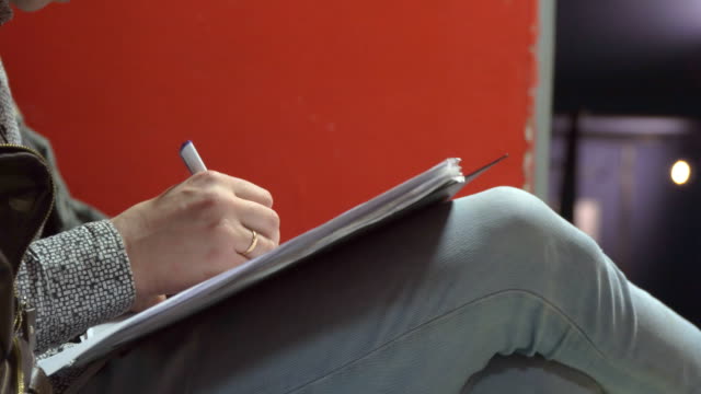 Hombre-escribe-sosteniendo-el-papel-sobre-sus-rodillas
