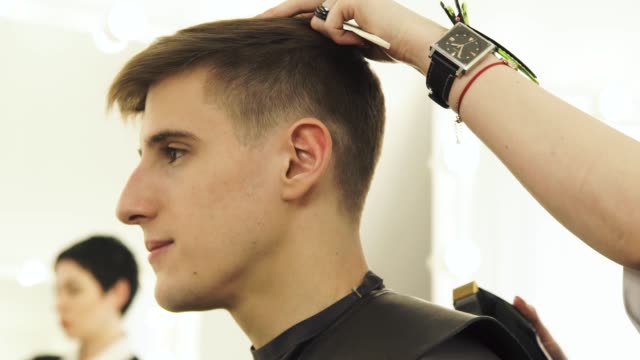 Hairdresser-cutting-hair-with-electrical-shaver-in-barbershop.-Haircutter-spraying-water-and-combing-wet-hair-during-hairdressing-in-beauty-studio.-Professional-male-hairstyle-in-salon