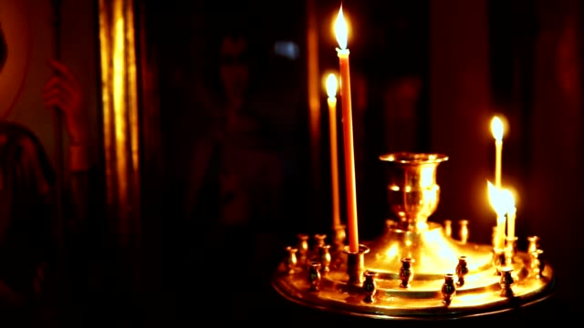 Leuchter-mit-brennenden-Kerzen-auf-dem-Hintergrund-der-Heiligen-Ikonen