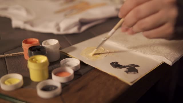 Artist-is-mixing-yellow-and-white-dyes-on-a-palette-before-drawing,-close-up
