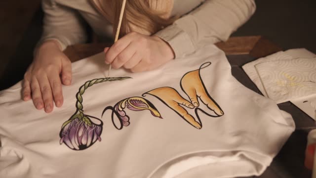 Woman-is-applying-pattern-on-a-white-sweatshirt,-close-up