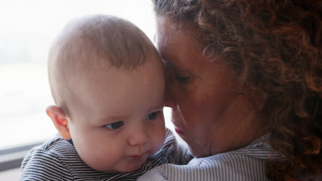 Baby-Enkel-über-Großmütter-Schulter-schaut,-wie-sie-ihm-kuschelt