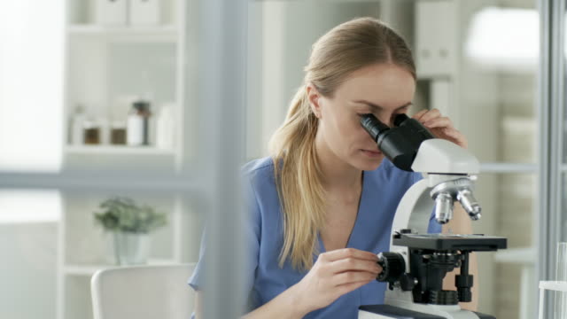 Mujer-examinando-muestras-con-microscopio