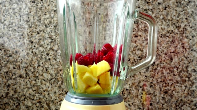 Filling-in-the-blender-of-apples,-raspberry-and-bananas.	Preparation-of-smoothie-in-the-blender.
