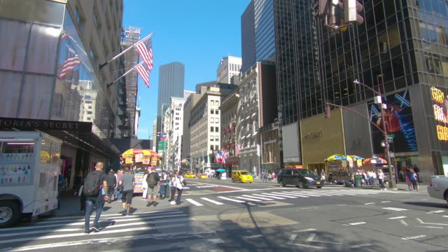 5th-Avenue-shopping-and-St-Patricks-Cathedral-with-traffic-passing-by-in-New-York-City,-Manhattan,-New-York
