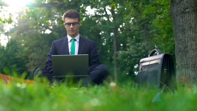 Young-manager-working-on-laptop-in-forest,-enjoying-nature,-escape-from-office