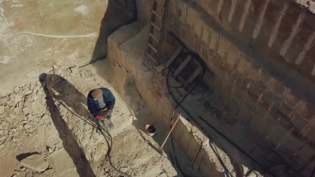 a-man-is-drilling-stones-with-using-power-tool-in-a-sand-quarry.
