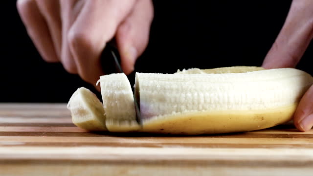Der-Mensch-ist-schneiden-Banane-auf-Schneidebrett-in-Zeitlupe