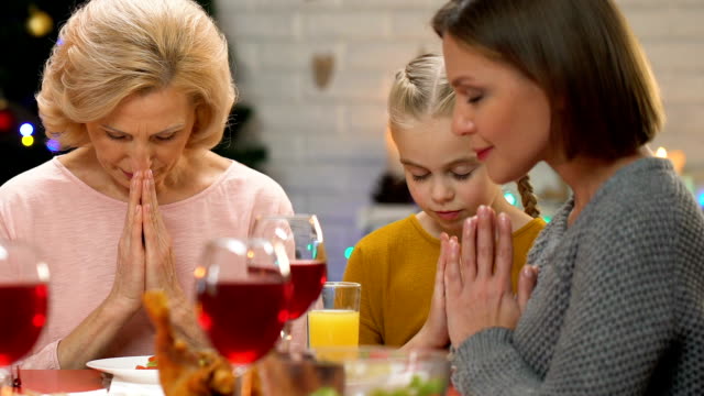 Female-family-members-praying-before-Christmas-dinner,-christian-traditions
