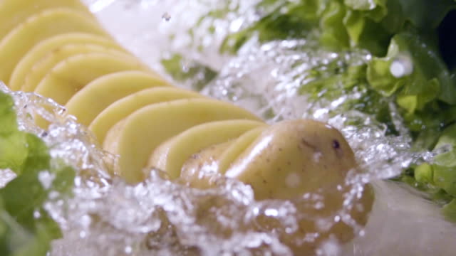 In-Scheiben-geschnittenen-Kartoffeln-fallen-in-den-nassen-Tisch.-Zeitlupe-480-fps