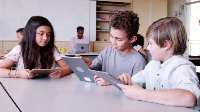 Drei-Kinder-mit-tablet-Computern-in-der-Grundschule-Klasse