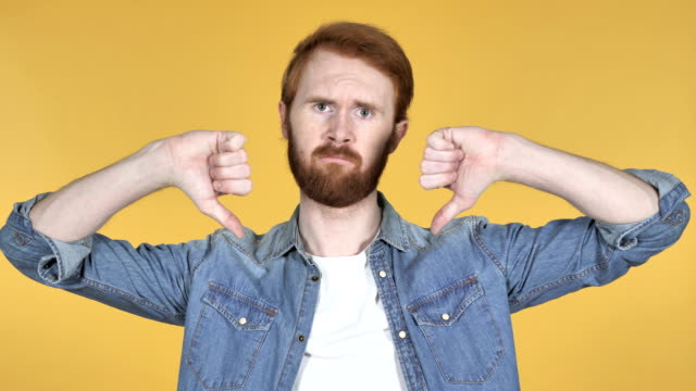 Redhead-Man-Gesturing-Thumbs-Down-Isolated-on-Yellow-Background