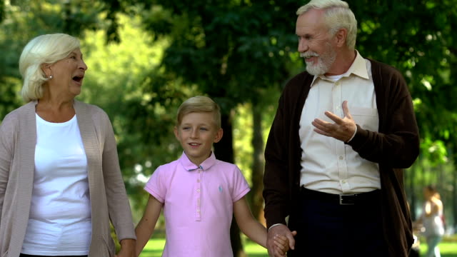 Little-boy-walking-with-his-grandparents-in-park,-enjoying-happy-time-together