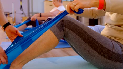 Entrenador-ayudando-a-mujer-mayor-en-la-realización-de-yoga-4k