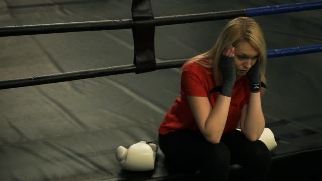 Tired-young-girl-sitting-in-the-ring-after-training