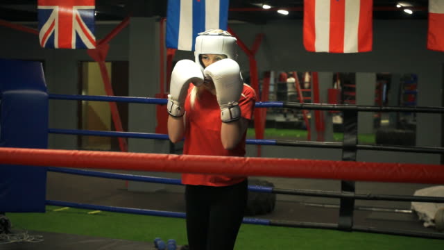 Young-girl-in-a-helmet-and-gloves-is-training-blows