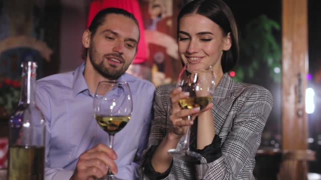 Pareja-brindando-con-copas-de-vino-blanco-en-cena-romántica