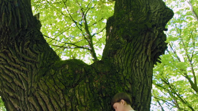 Mädchen-umarmt-einen-großen-Baum-im-Wald.-Kamera-bewegen.