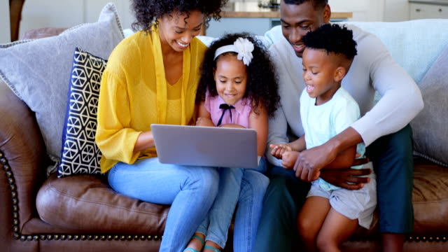 Vorderansicht-der-Familie-black-mit-Laptop-im-Wohnzimmer-zu-Hause-4k