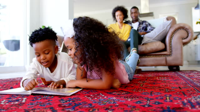 Front-view-of-cute-black-kids-reading-story-book-in-living-room-at-comfortable-home-4k
