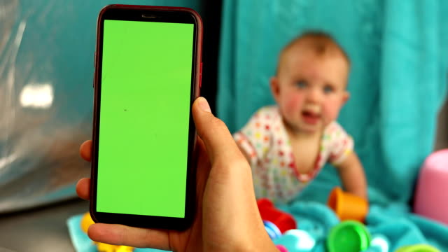 Hand-Mutter-hält-Telefon-Hintergrundkind