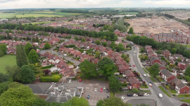 Aerial-footage-of-the-town-known-as-Crossgates-in-the-Leeds-area-of-West-Yorkshire-in-the-UK,-showing-a-typical-British-town-and-street-with-rows-of-houses-and-light-traffic-on-the-main-roads.