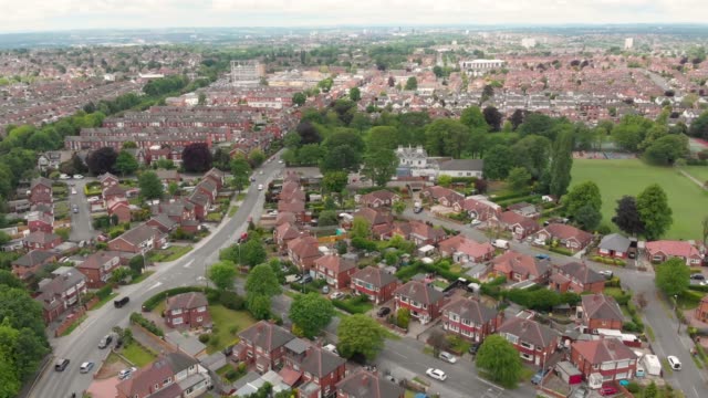 Aerial-footage-of-the-town-known-as-Crossgates-in-the-Leeds-area-of-West-Yorkshire-in-the-UK,-showing-a-typical-British-town-and-street-with-rows-of-houses-and-light-traffic-on-the-main-roads.
