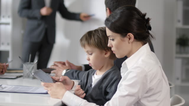 Madre-usando-la-tableta-con-el-hijo-pequeño-durante-la-reunión-corporativa