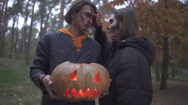 Mann-und-Frau-in-Halloween-Kostümen-mit-Make-up-suchen-in-die-Kamera-mit-ernsten-beängstigend-Gesichter-im-Herbst-park