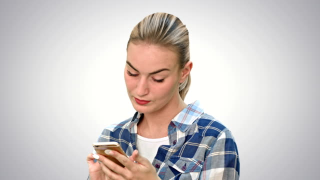 Troubled-woman-reading-bad-text-news-on-phone-touching-her-head-in-misery-on-white-background