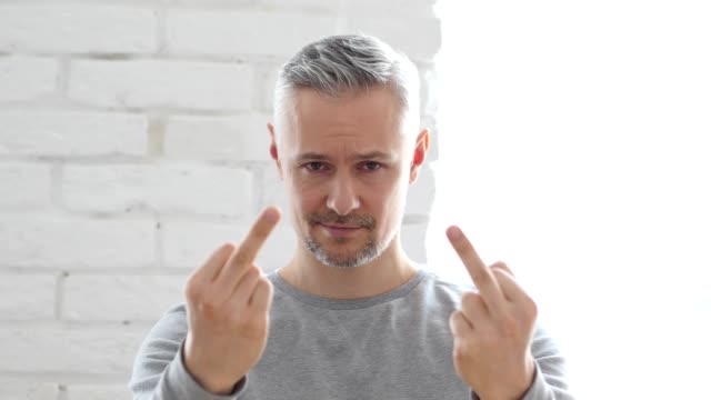Middle-Aged-Man-Showing-Middle-Finger,-Sitting-in-Office