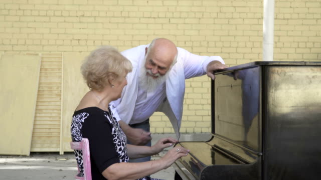 Alter-bärtiger-Mann-bietet-seine-Frau-Klavier-spielen