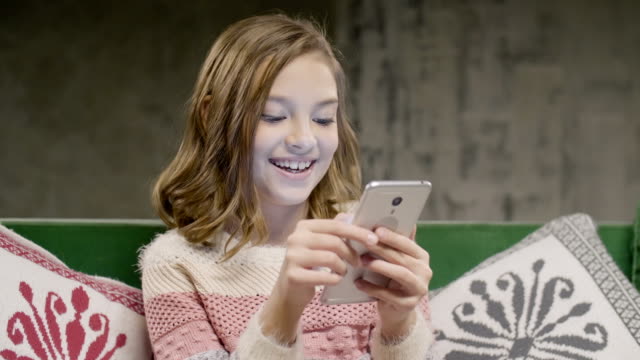 Teen-girl-chat-with-friend-by-smartphone-at-home