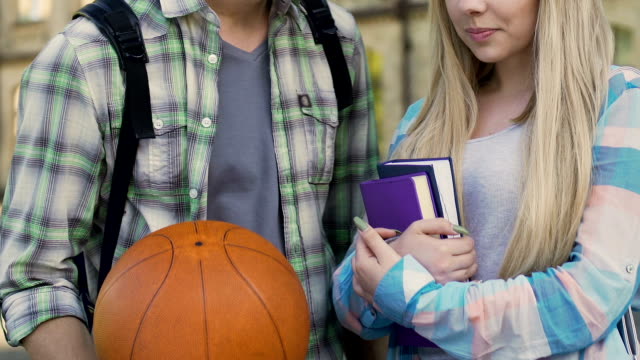 Kerl-mit-Basketball-Ball-im-Gespräch-mit-Mädchen-mit-Büchern,-beliebte-Kerl-und-Nerd,-flirt