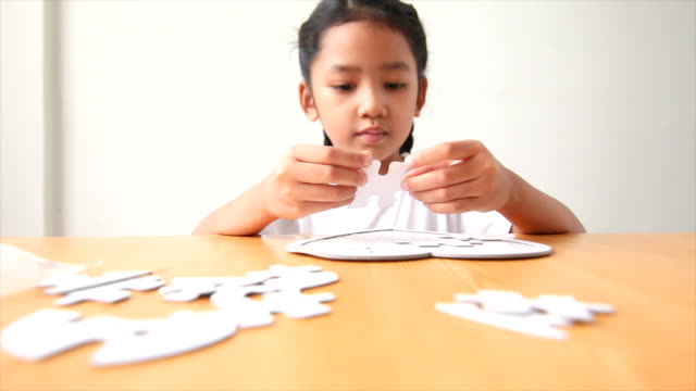 Asiático-poco-chica-jugar-jigsaw-puzzle-seleccionar-centrarse-en-profundidad-de-la-mano-de-campo