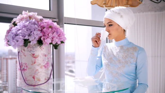 Junge-muslimische-Braut-im-blauen-Hochzeitskleid-trinken-Sie-eine-Tasse-Kaffee