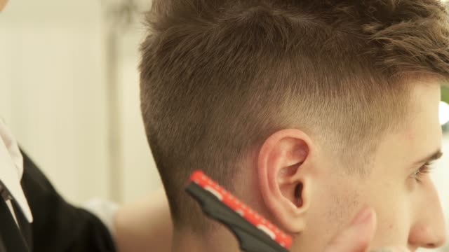 Hair-stylist-working-in-hairdressing-salon-close-up.-Hairdresser-finish-hair-style-after-cutting.-Male-hairstyle-in-barber-shop