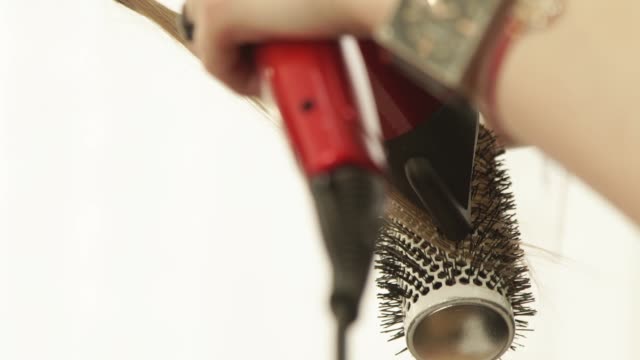 Haircutter-using-dryer-and-hairbrush-for-drying-and-styling-long-hair-after-hairdressing-in-beauty-studio.-Close-up-haircutter-finish-hairstyling-after-haircut-in-hairdressing-salon